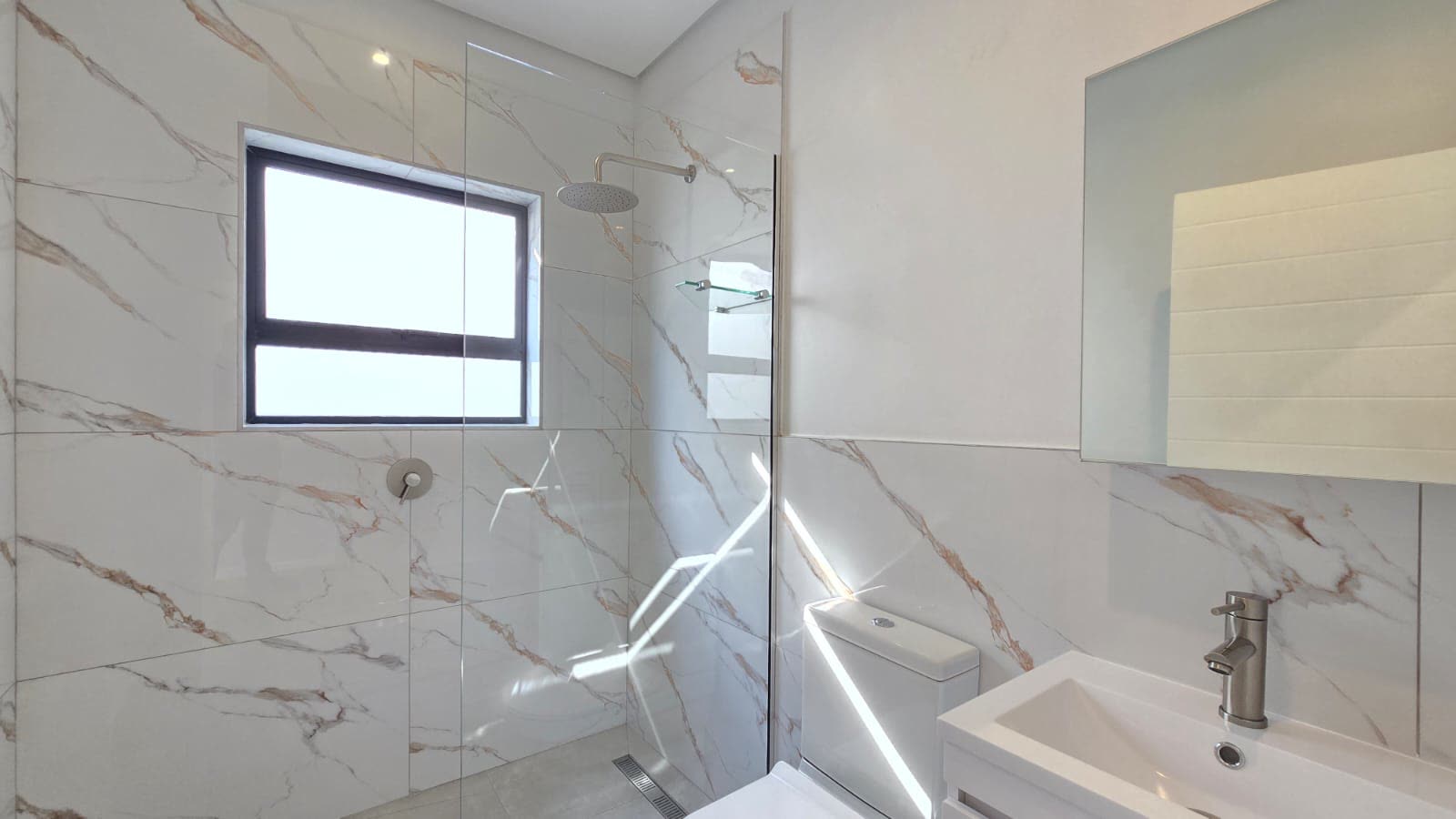 Main en-suite with marble-look tiling and walk-in shower