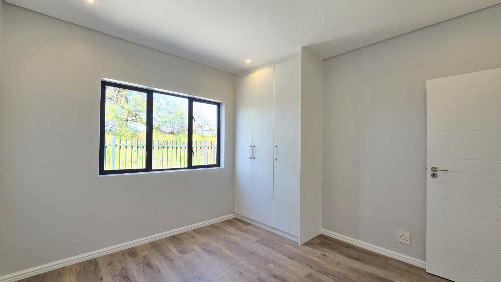Bedroom with built-in cupboards looking onto the garden