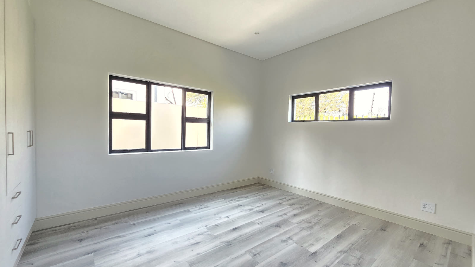 Bedroom with twin windows and wood-look flooring